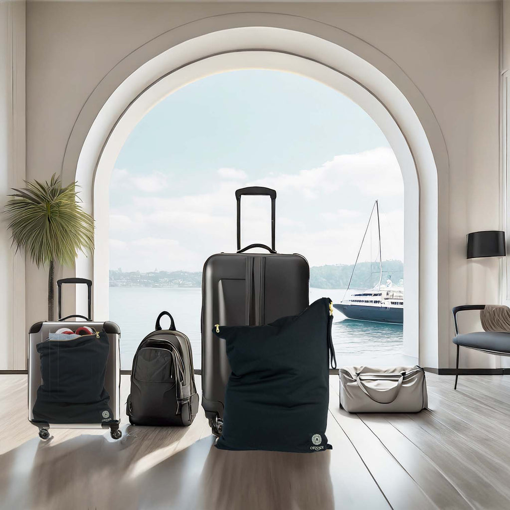 Collection of black suitcases and Ornadi  waterproof bags in a modern hotel lobby with a large window sailboat view.